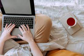 Crop person using laptop with empty screen in bed near cup of tea placed on  notebook · Free Stock Photo